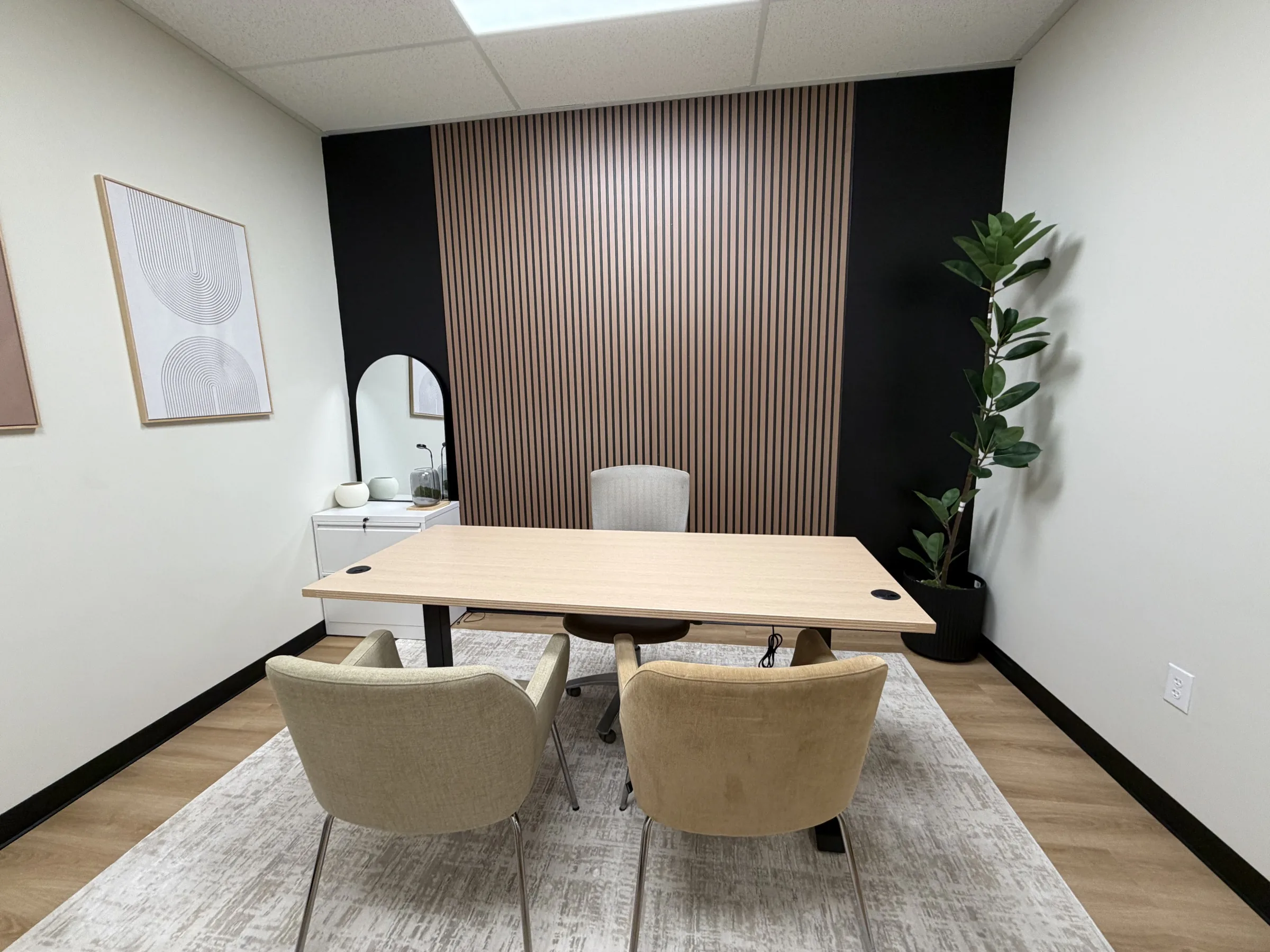 Furnished private office with a desk, guest chairs, and wood slat accent wall in Las Vegas